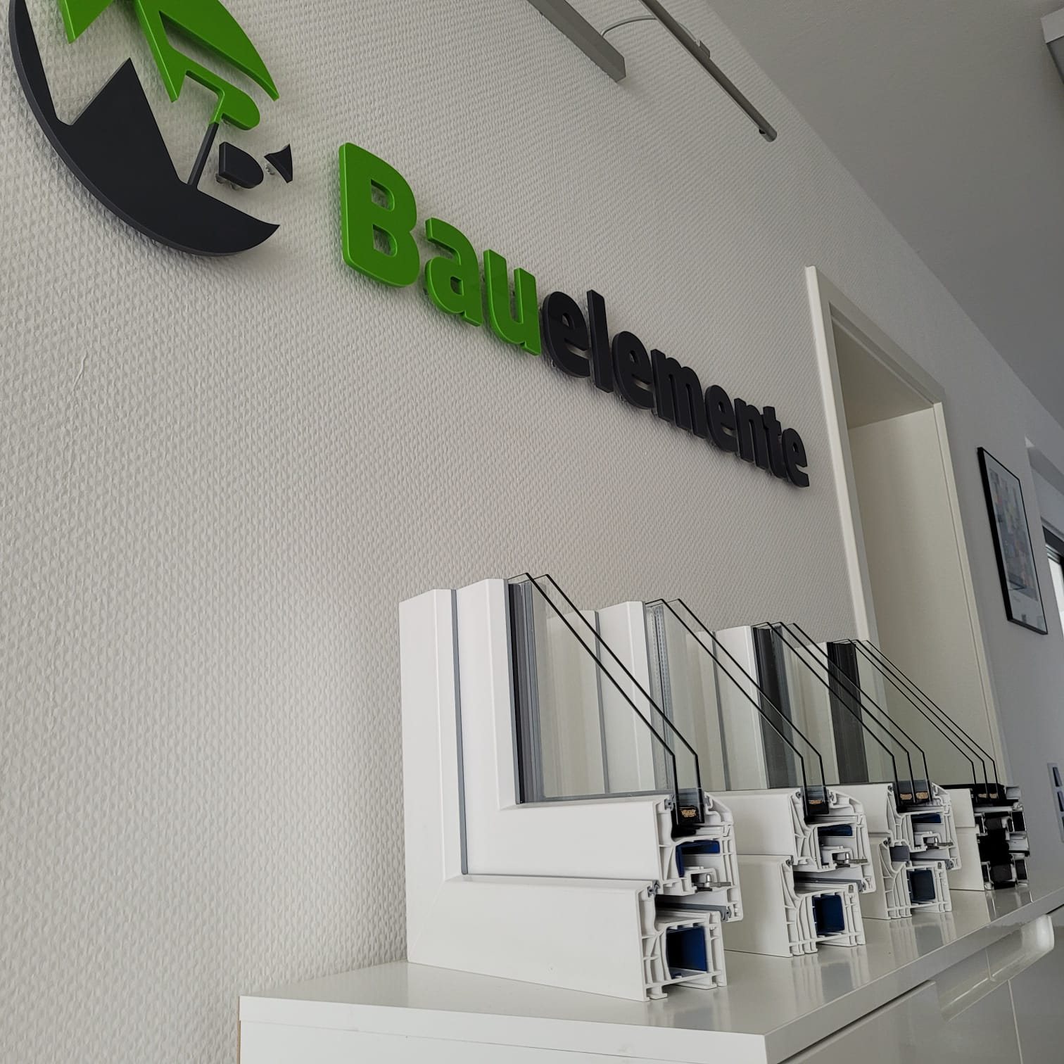 Wand mit WB Bauelemente Logo und mehreren Fensterprofilen